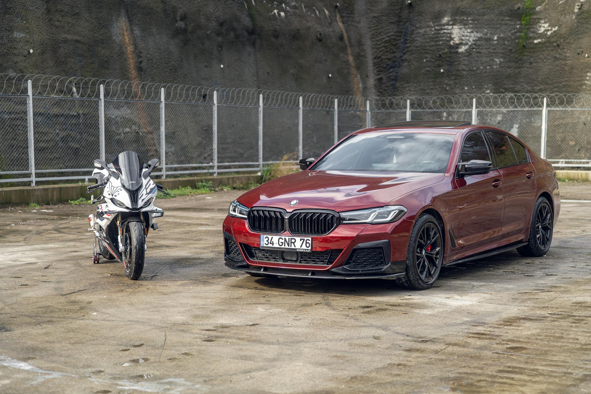 Czerwony luksusowy sedan i motocykl sportowy zaparkowane na betonowym placu