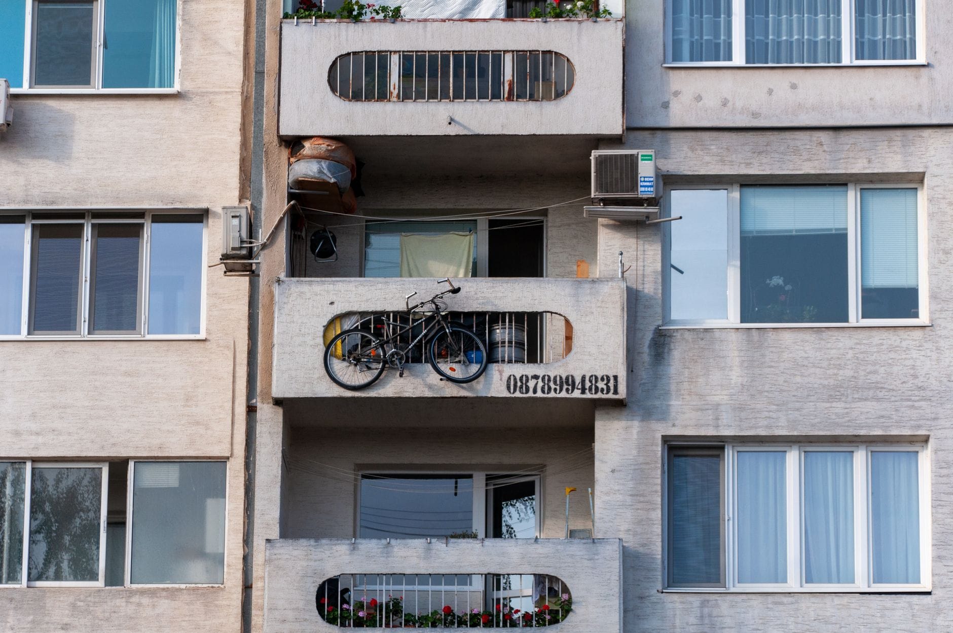 Jak zamienić niewielki balkon w dodatkową przestrzeń do przechowywania Balkon w bloku z rowerem i klimatyzatorem jako miejsce przechowywania