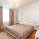 Łóżko z narzutą w klasycznej sypialni z lampami i żyrandolem